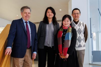 A group of four people stand together on the steps in AB1 in Alexandria.