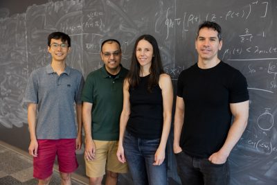 VTQ researchers pose for a photo in front of chalk board with equations