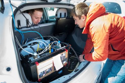 Two students examine the system inside an autonomous vehicle