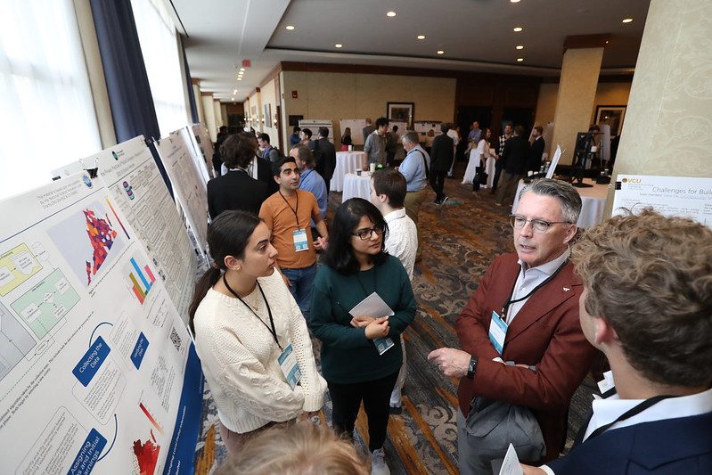 President Tim Sands (second from right) talks with a grounp of students at a poster session.