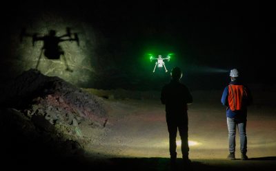 Two people fly a drone at nighttime.